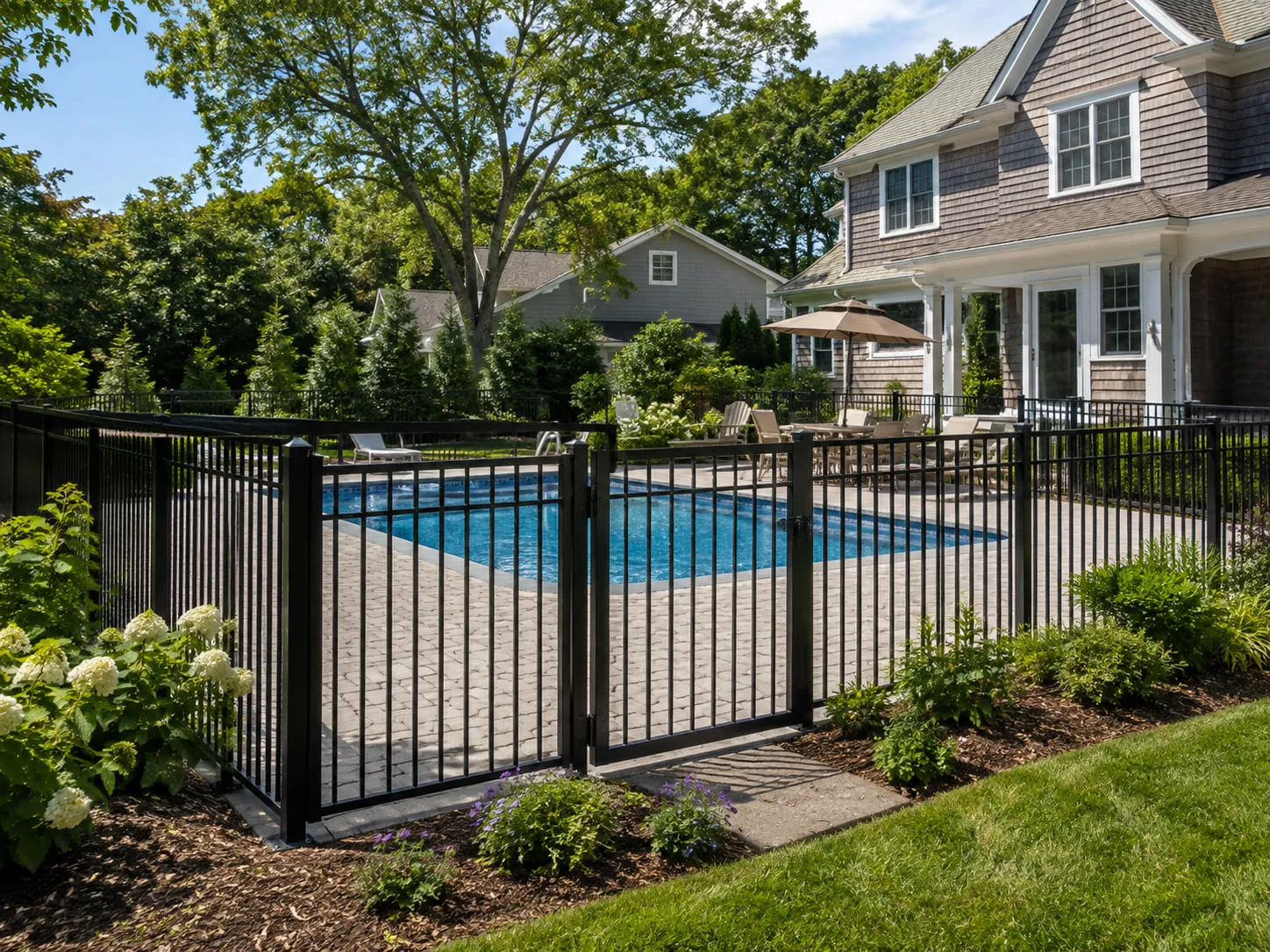 Black powder-coated aluminum pool fence with a self-closing gate enclosing a residential swimming pool
