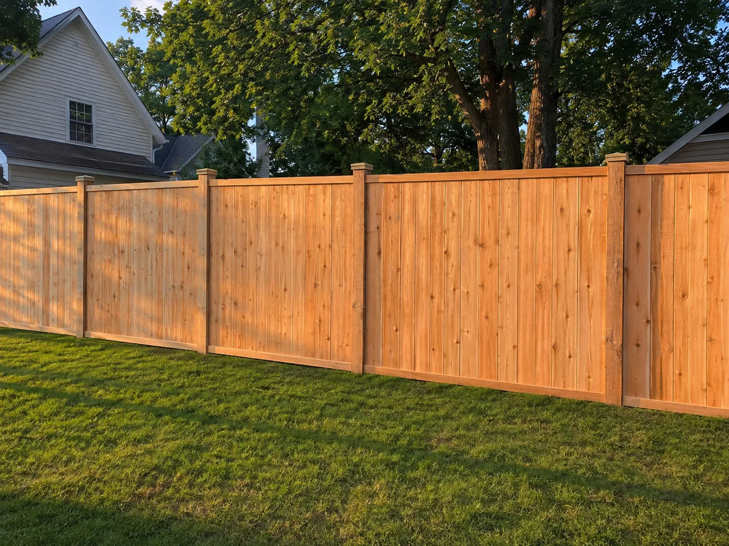 New cedar board privacy fence with a level top line running along a backyard in Plymouth, MA